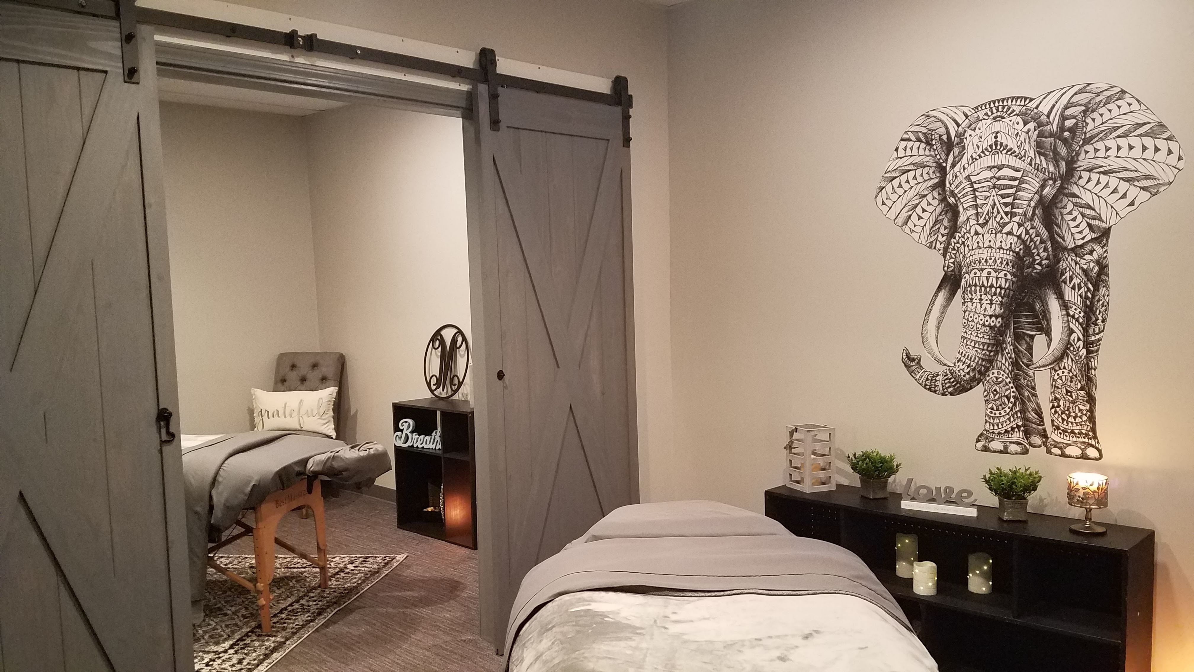 The signature elephant treatment room, barn doors, candlelight, and a second bed beyond
